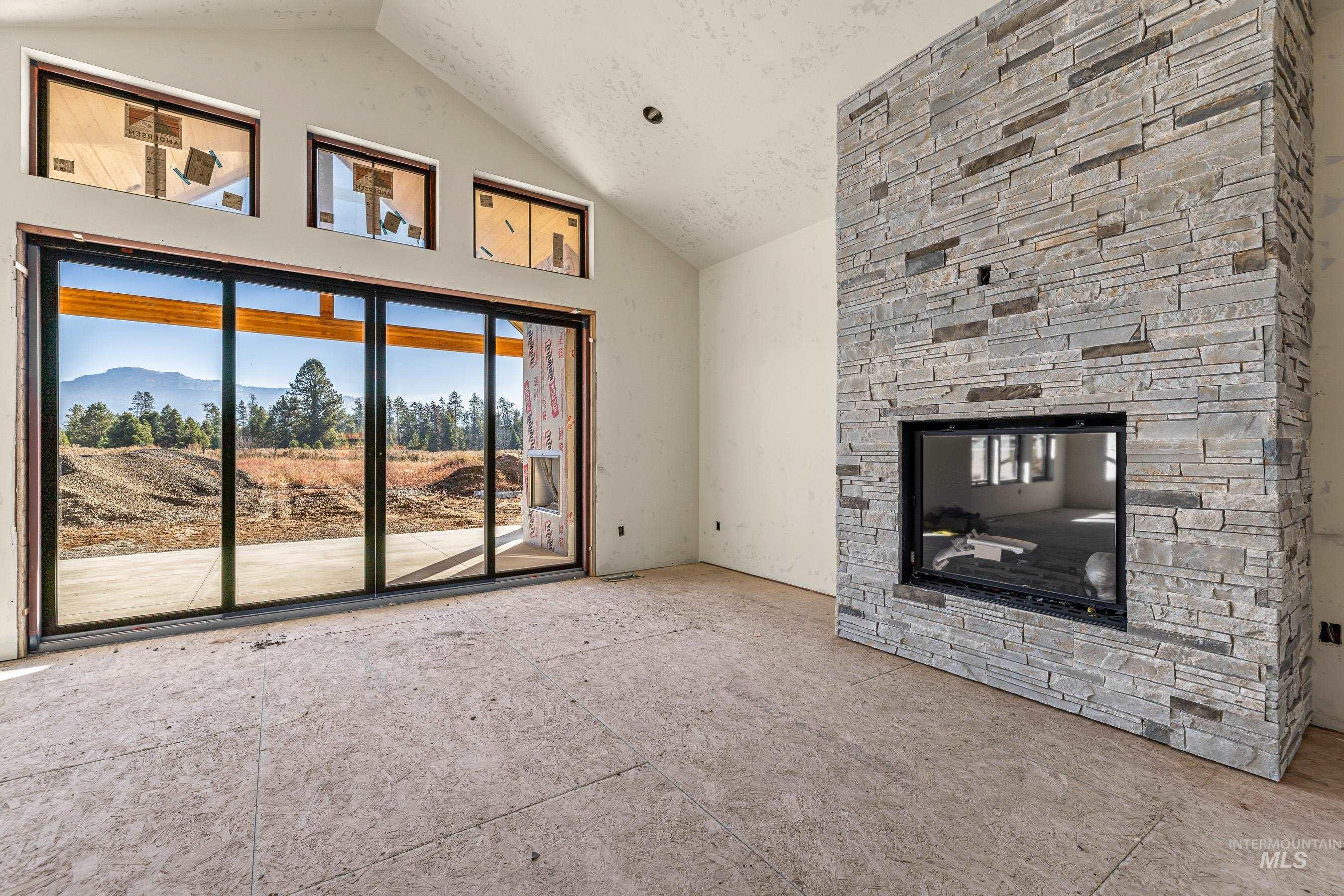 Unfurnished living room featuring a stone fireplace, high vaulted ceiling, and a mountain view