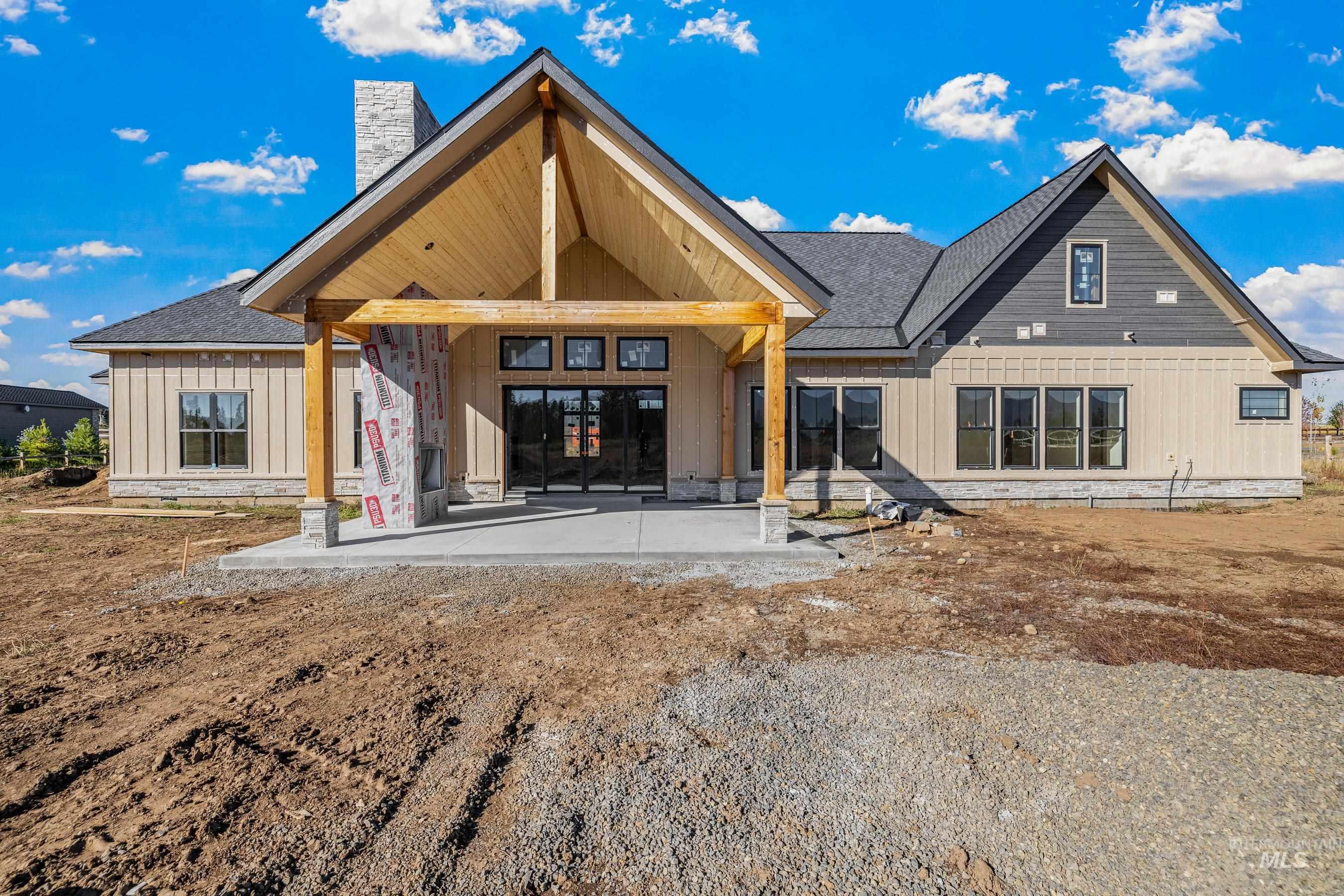 Back of property featuring a patio, a chimney, board and batten siding, and roof with shingles