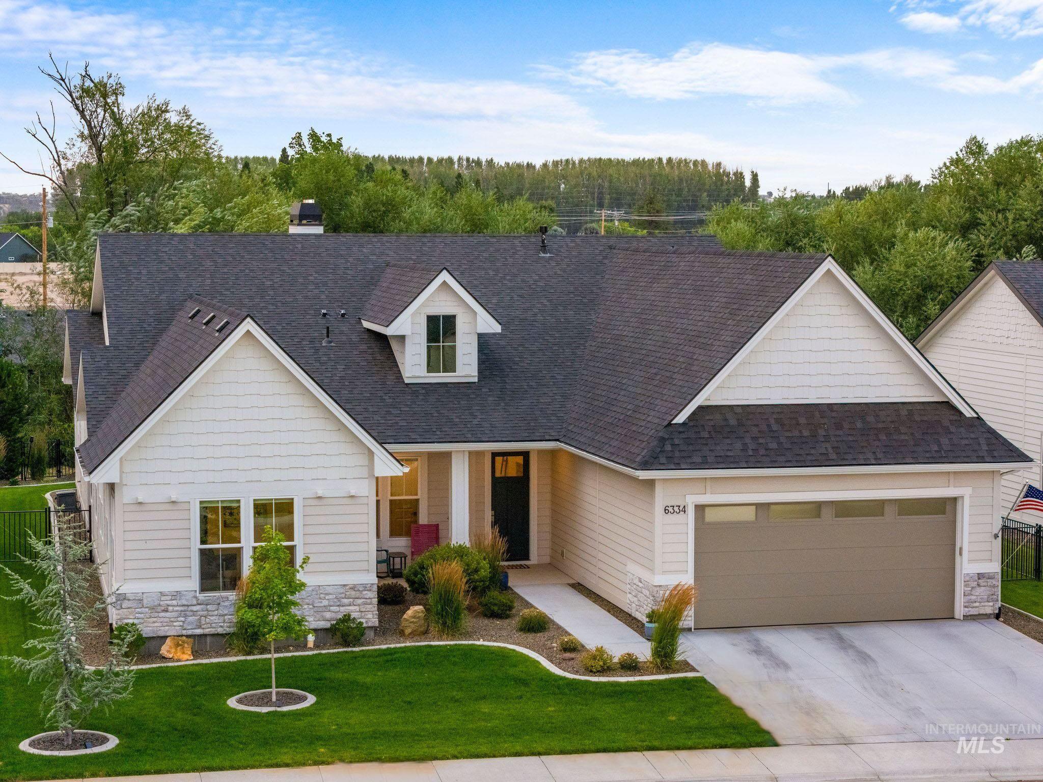 View of front facade featuring stone siding, a shingled roof, and a front yard