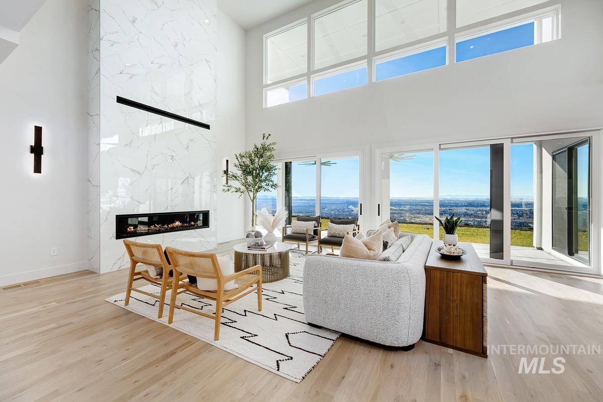 Living room with a towering ceiling, light wood finished floors, and a fireplace