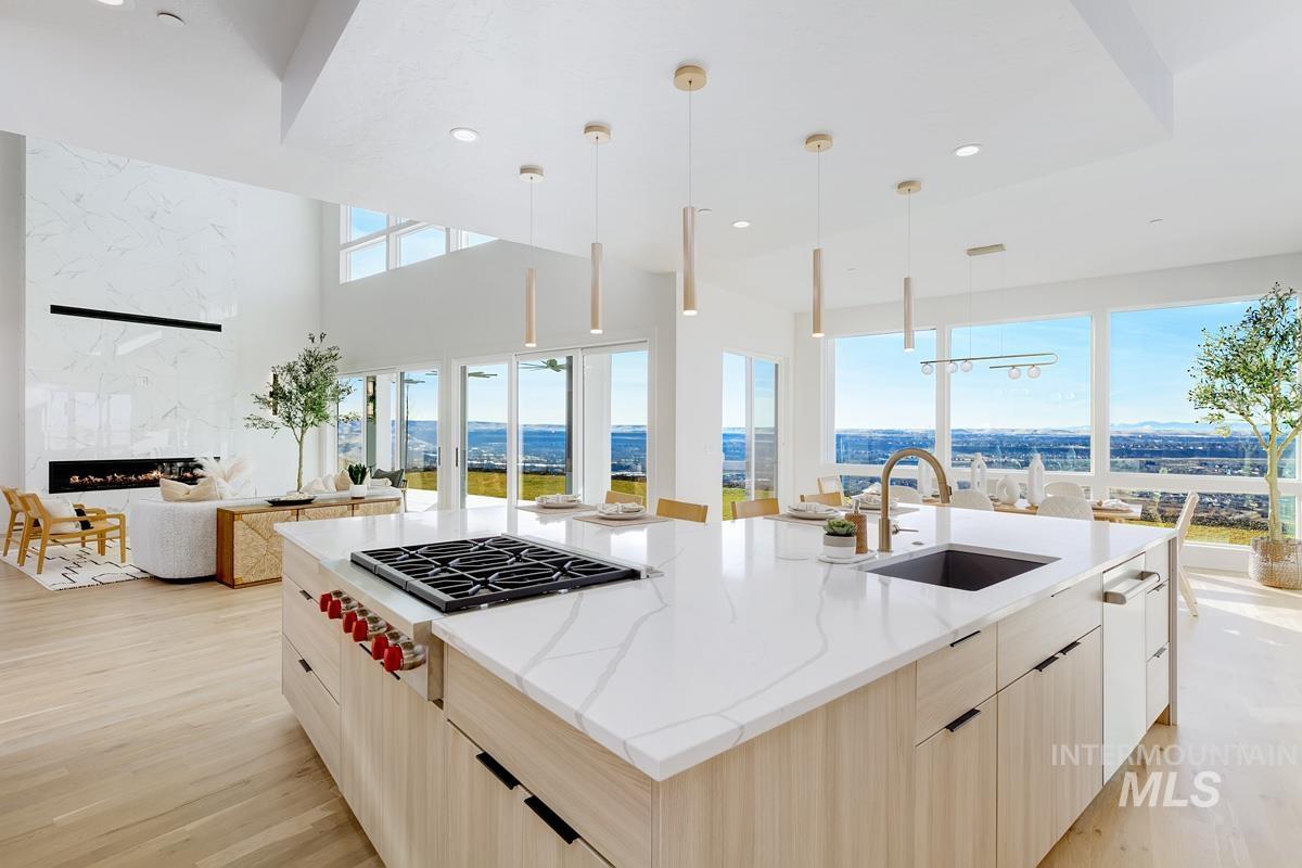 Kitchen featuring modern cabinets, light brown cabinets, open floor plan, stainless steel gas cooktop, and decorative light fixtures