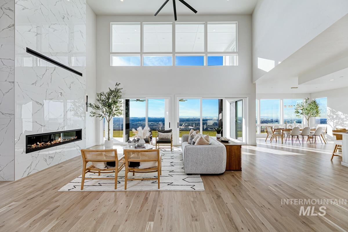 Living room featuring a high end fireplace, light wood-style flooring, and a high ceiling
