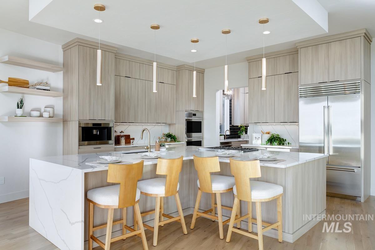Kitchen featuring light stone counters, light brown cabinets, modern cabinets, stainless steel appliances, and recessed lighting