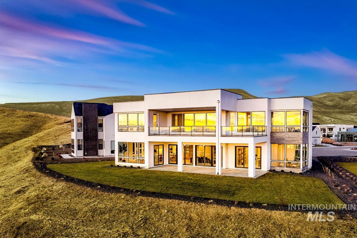 Back of house featuring a balcony, a patio, a mountain view, stucco siding, and a yard