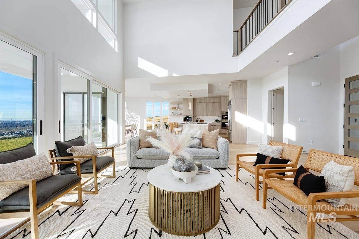 Living area with plenty of natural light, a towering ceiling, and light wood-type flooring