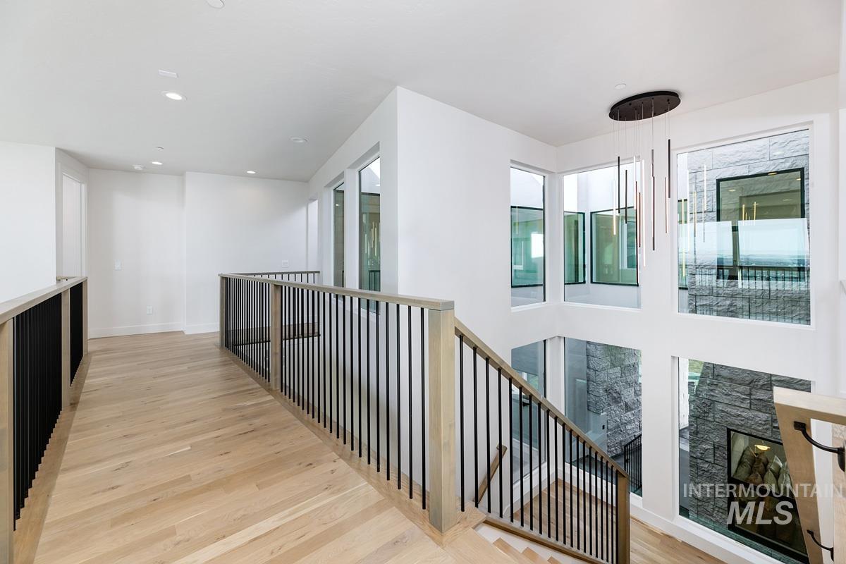 Corridor with light wood-type flooring, an upstairs landing, and recessed lighting