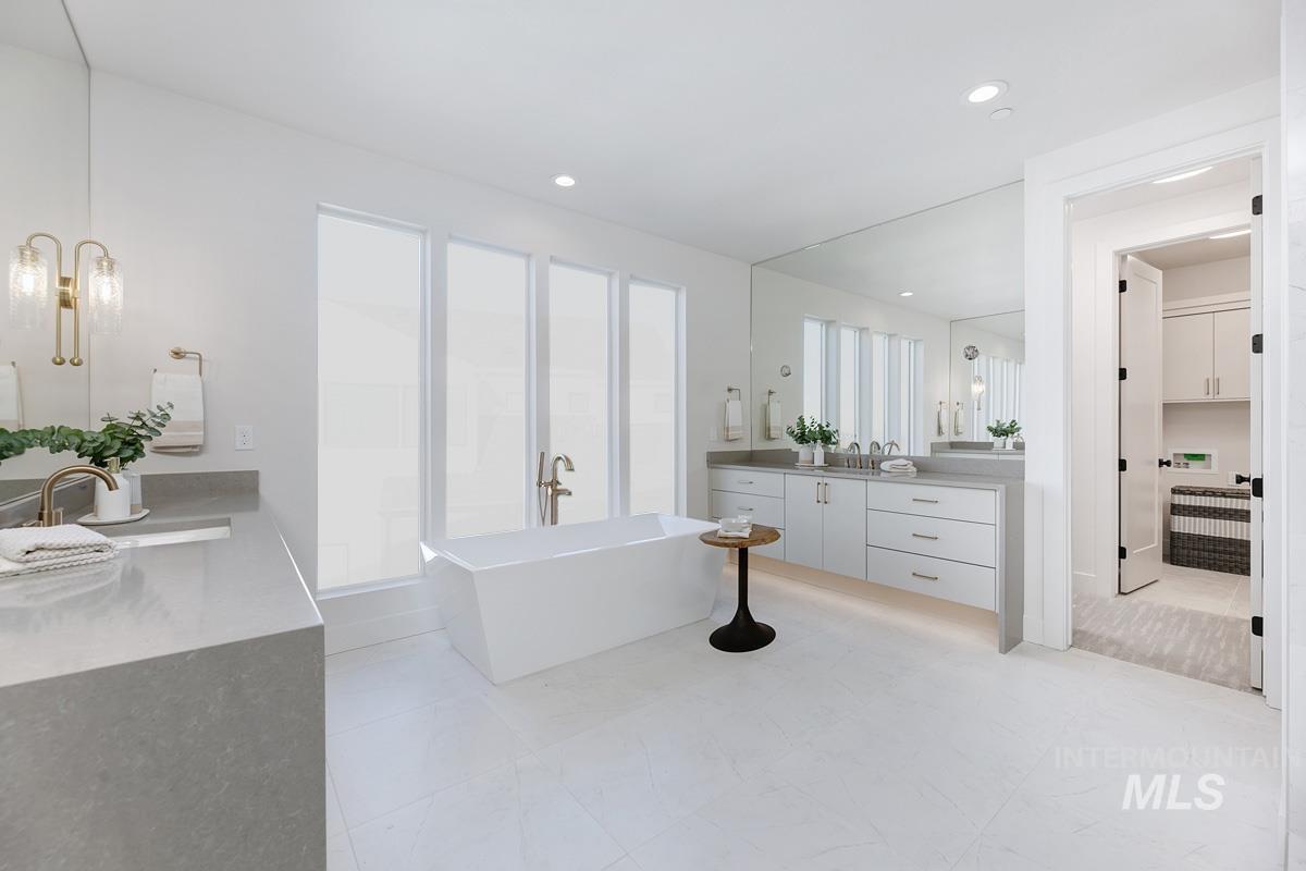 Bathroom with a freestanding bath, vanity, recessed lighting, and a closet