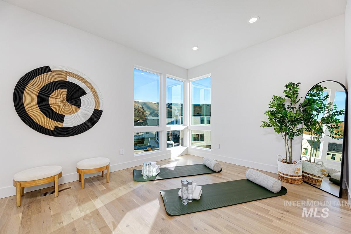 Workout room with light wood-style floors and recessed lighting