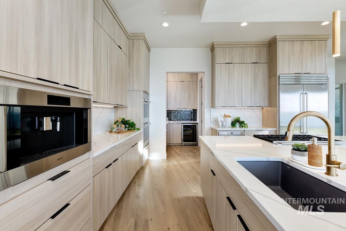 Kitchen with light brown cabinets, light stone countertops, light wood finished floors, modern cabinets, and recessed lighting