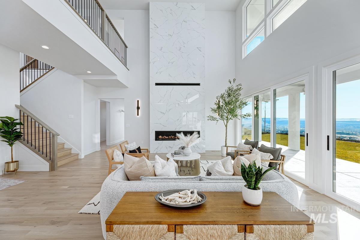 Living area featuring a premium fireplace, a high ceiling, stairs, and light wood-style flooring