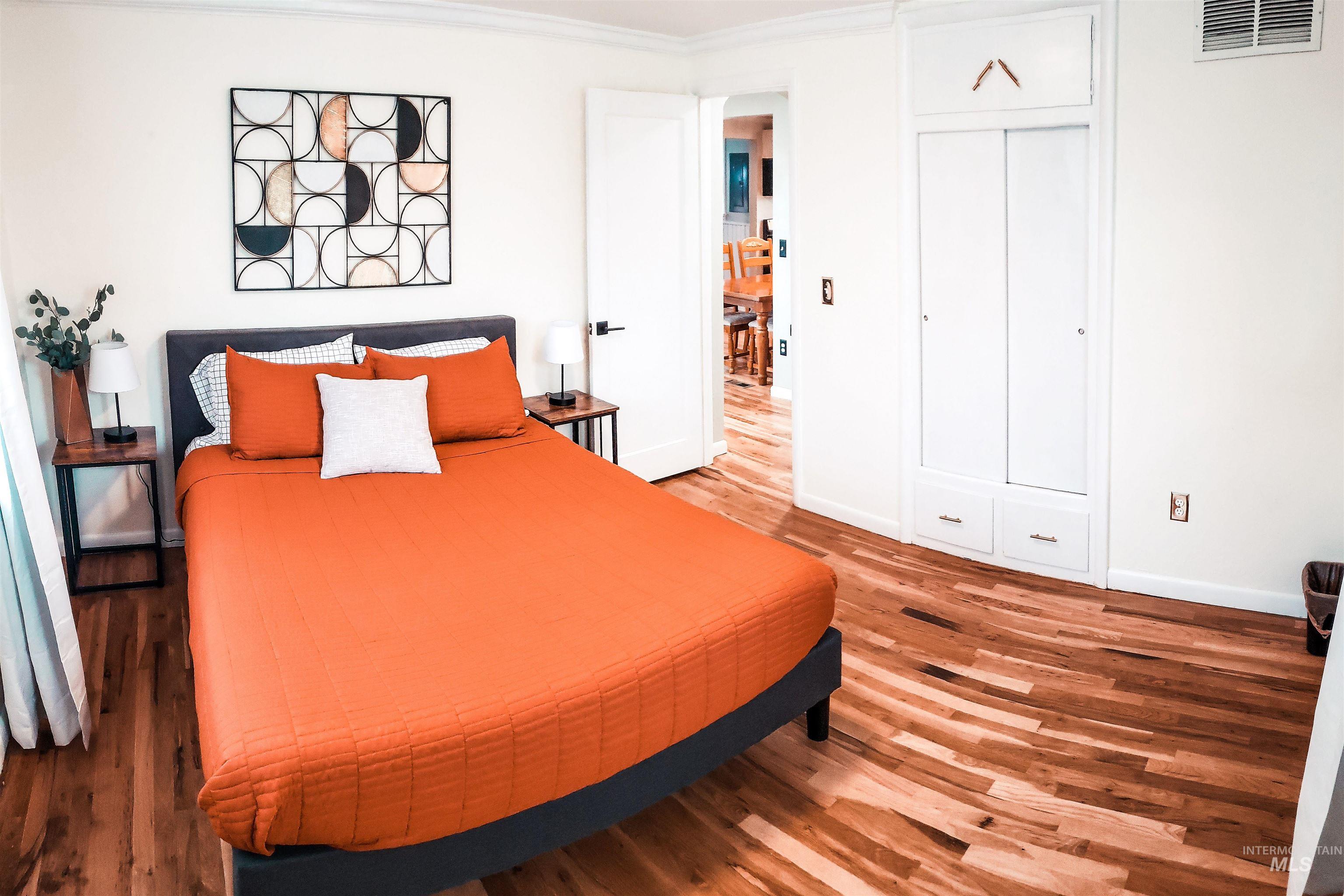 Wood-finish flooring throughout, featuring a built-in closet with sliding doors and lower drawers