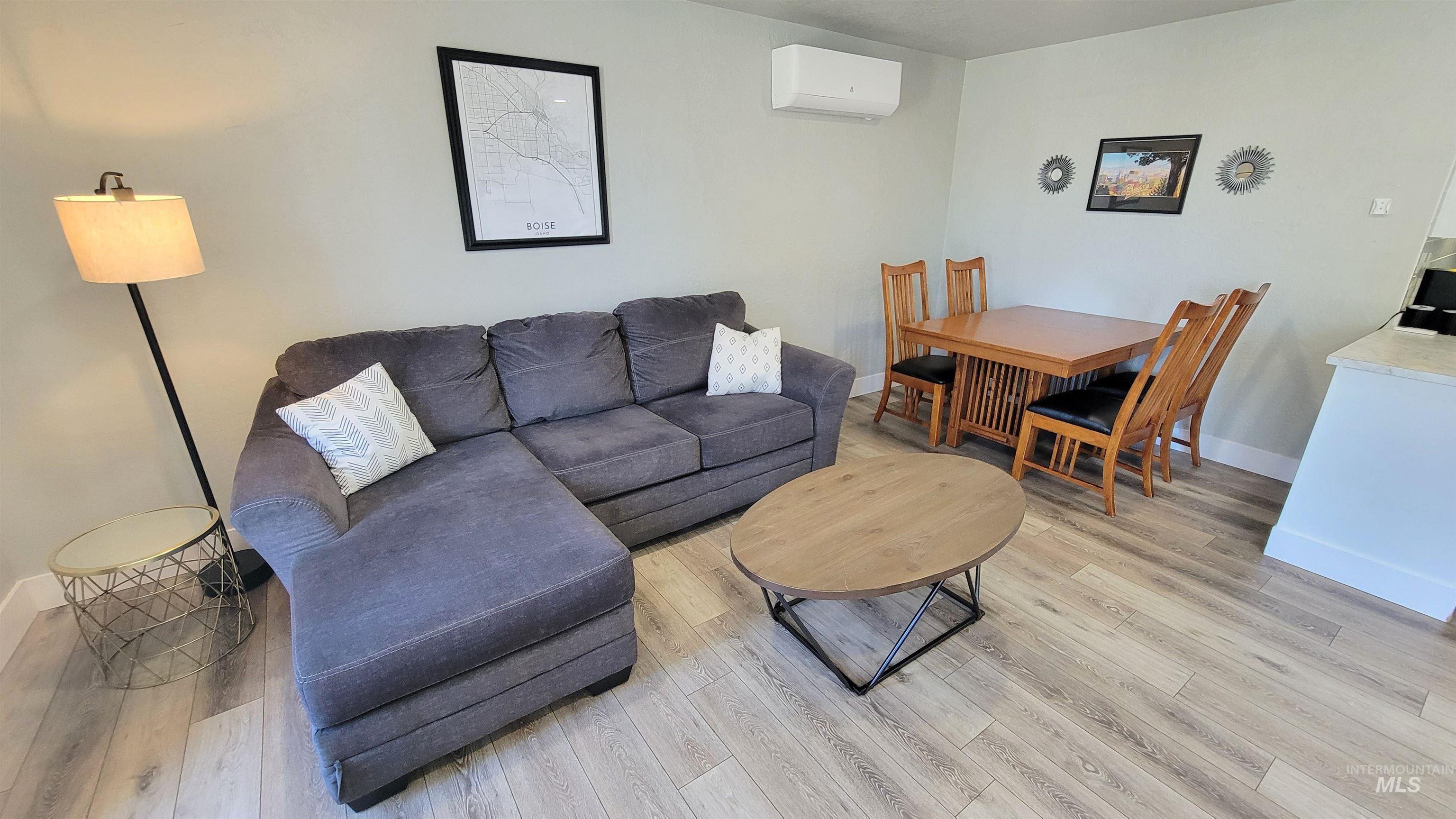 Open-concept living space featuring wood-finish flooring, a wall-mounted mini-split HVAC system, and light-toned wall paint