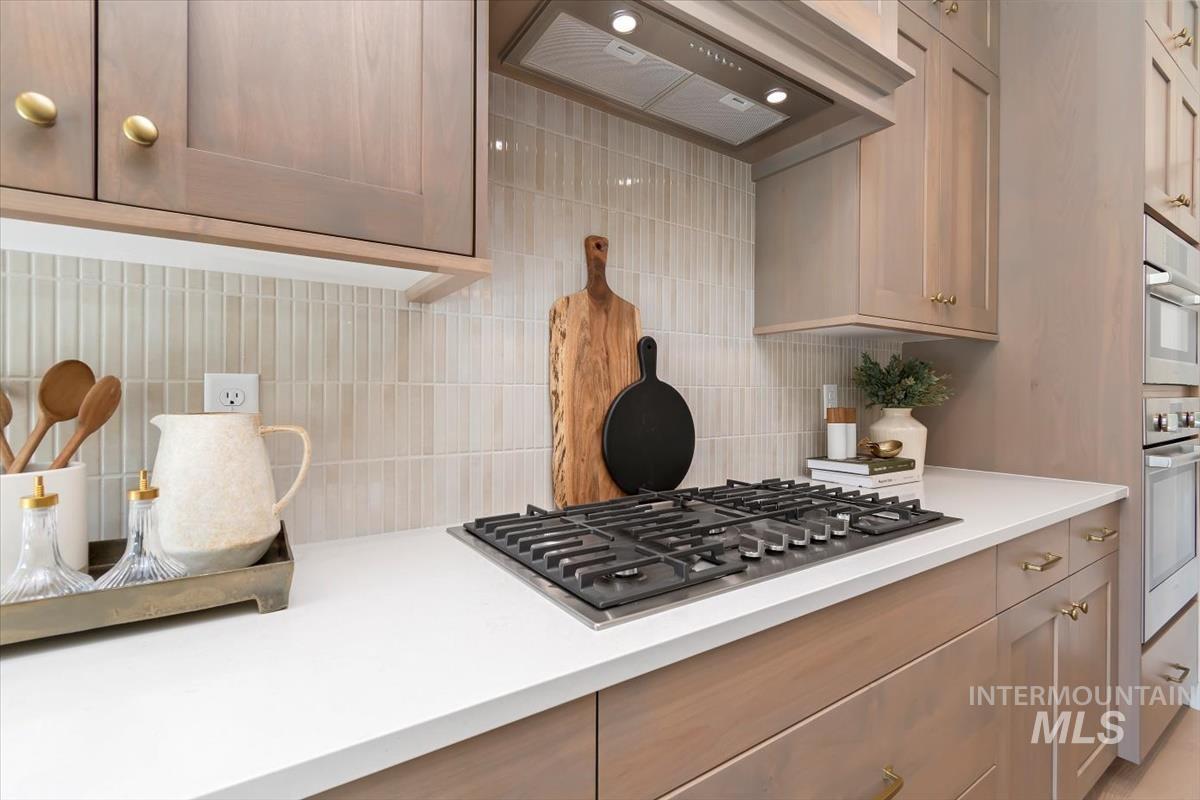 Kitchen featuring stainless steel appliances, backsplash, and light stone counters