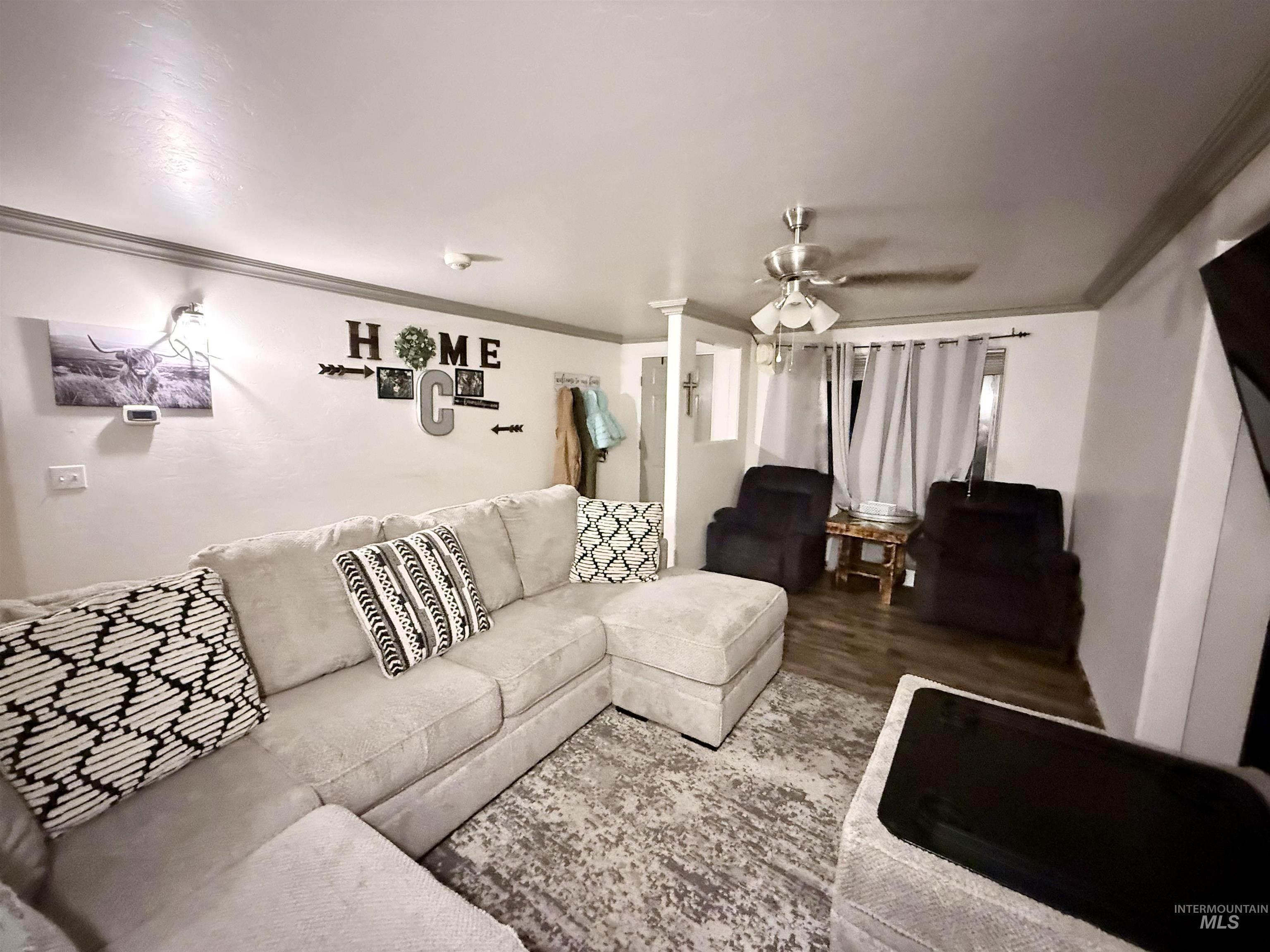 Living area featuring crown molding, wood finished floors, and ceiling fan