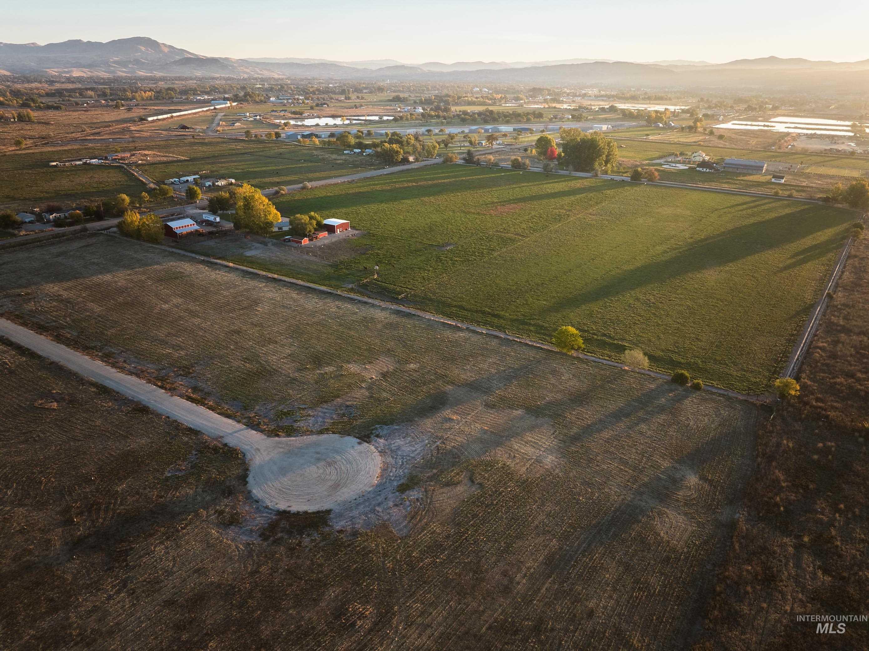 Aerial view of property and surrounding area featuring rural landscape, a mountain backdrop, and large plots for crops
