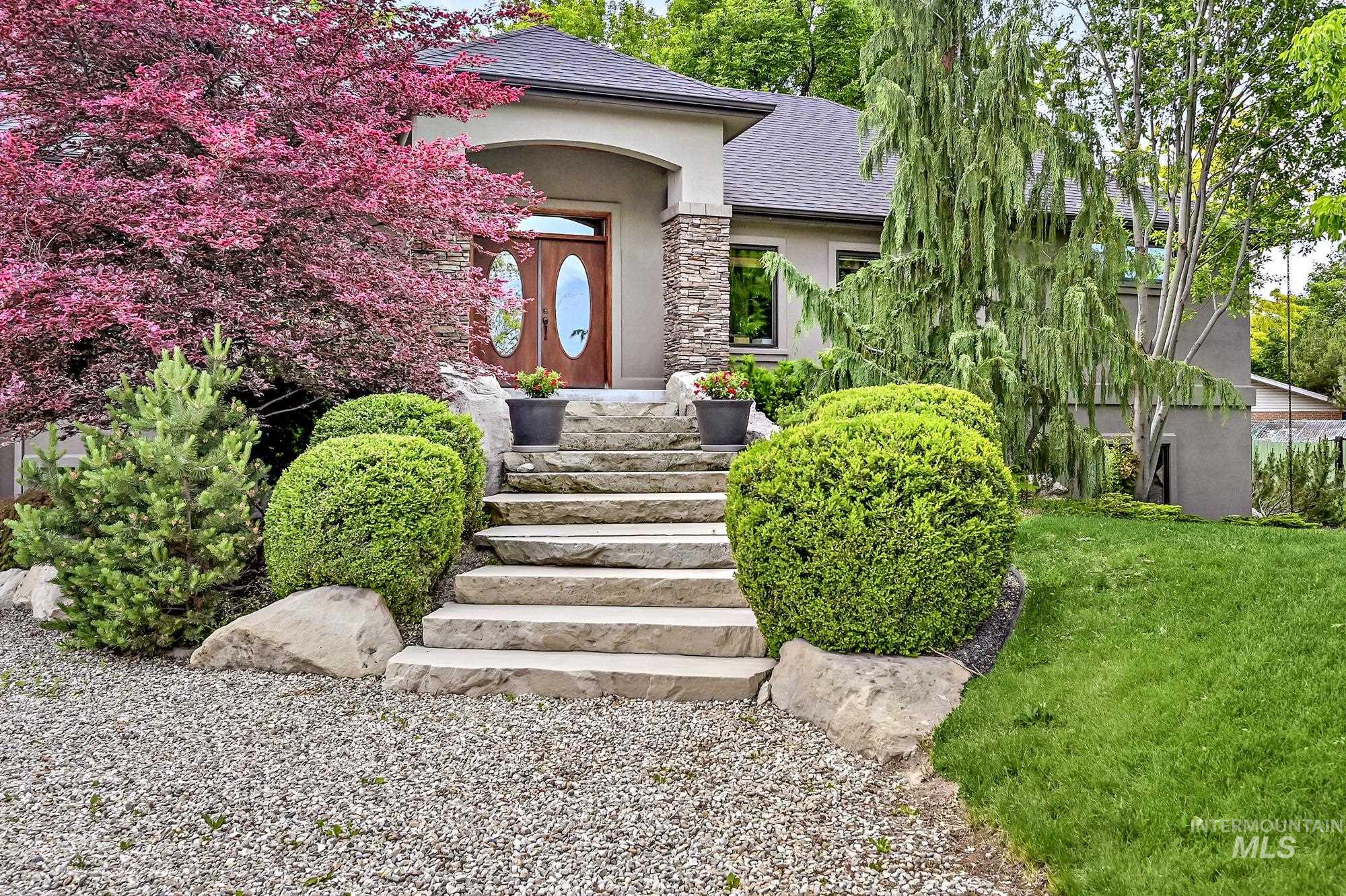 Entrance to property featuring stucco siding, roof with shingles, stone siding, and a yard