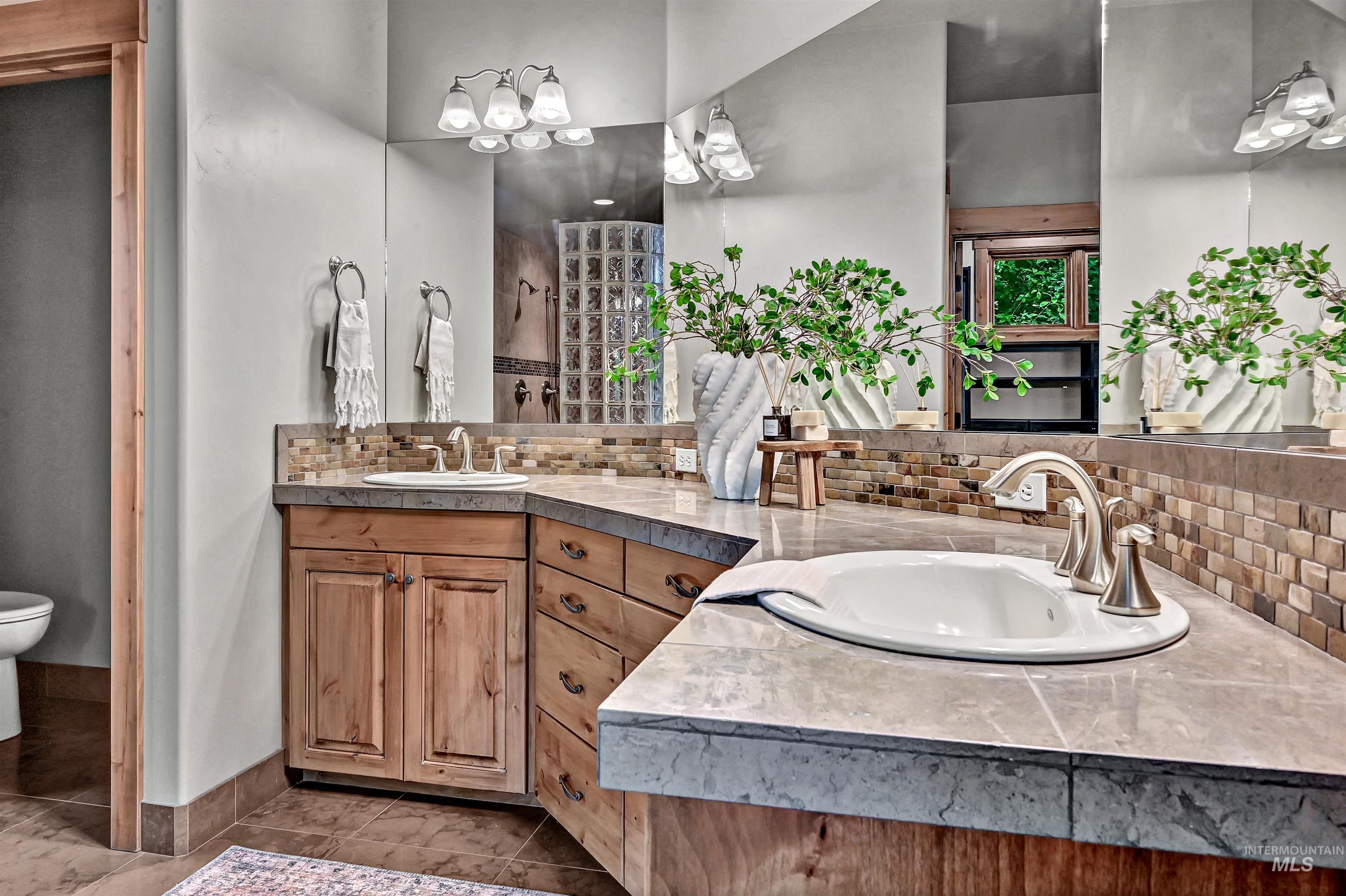 Bathroom with tasteful backsplash, two vanities, and tile patterned floors