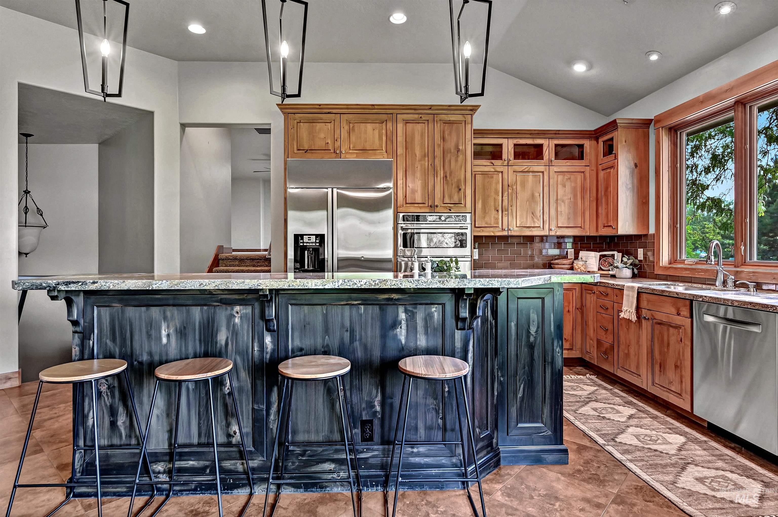 Kitchen featuring brown cabinetry, a center island, a kitchen breakfast bar, appliances with stainless steel finishes, and pendant lighting