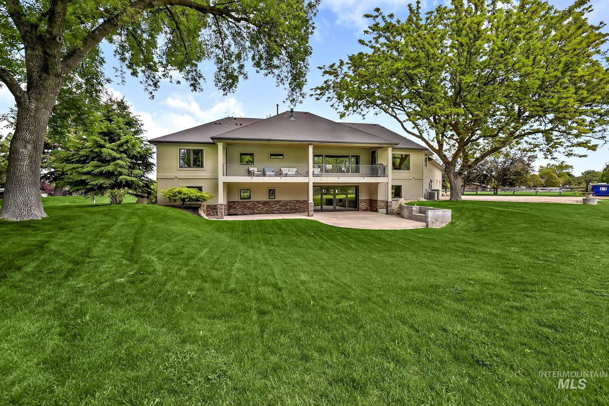 Rear view of house featuring a patio, stucco siding, a lawn, and a balcony