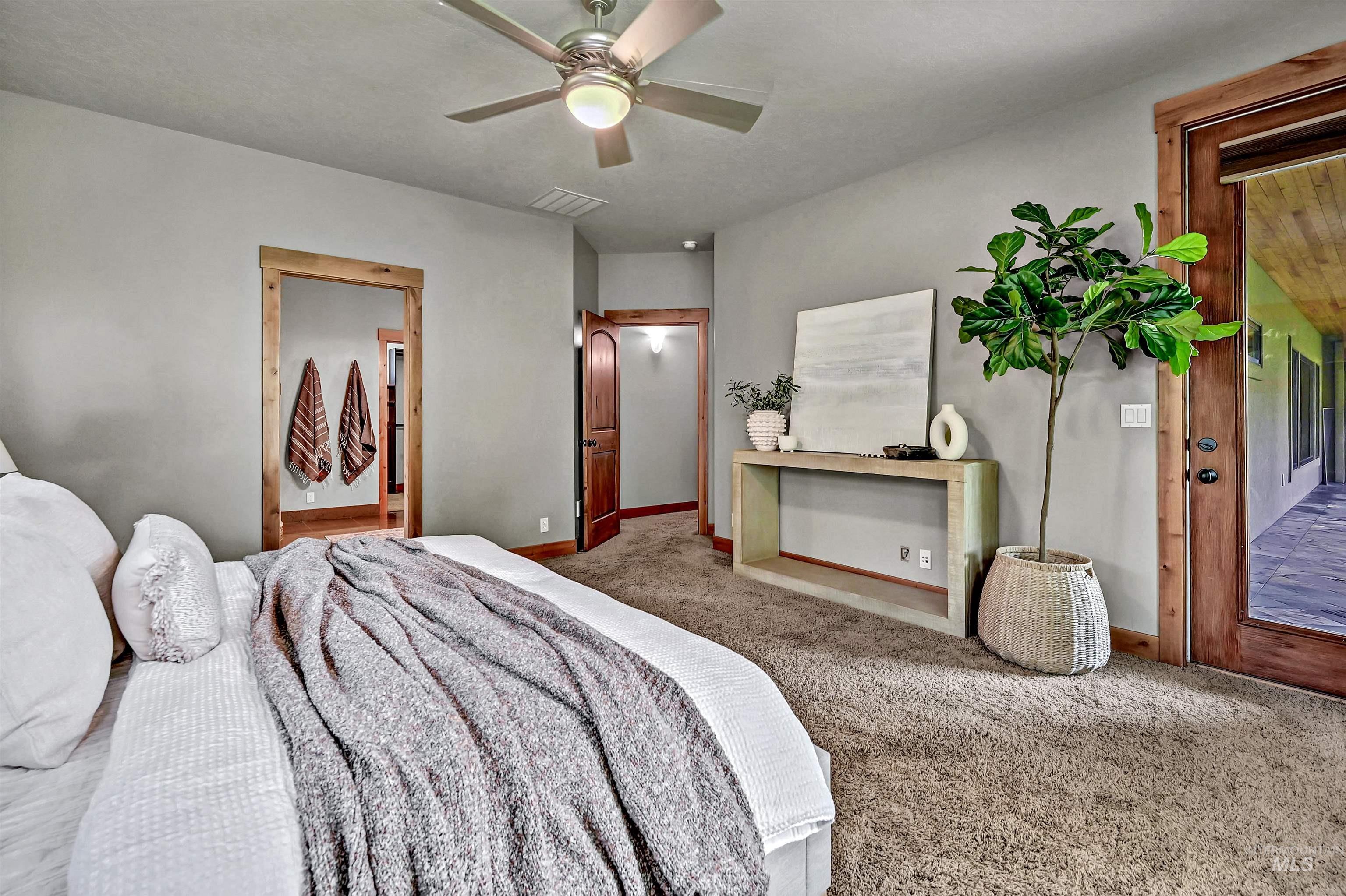 Carpeted bedroom with ceiling fan and connected bathroom