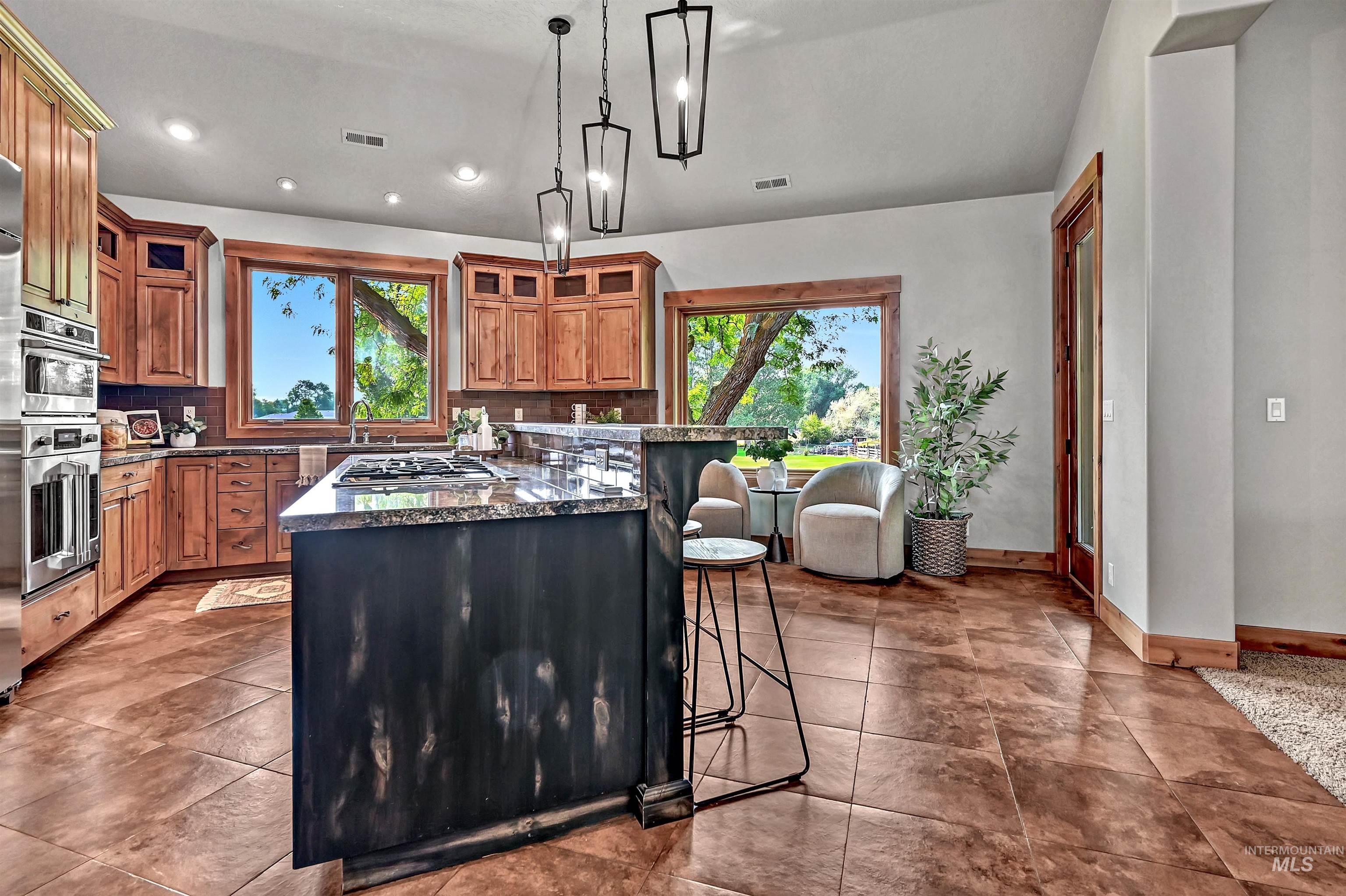 Kitchen with brown cabinets, a breakfast bar, backsplash, a center island, and decorative light fixtures