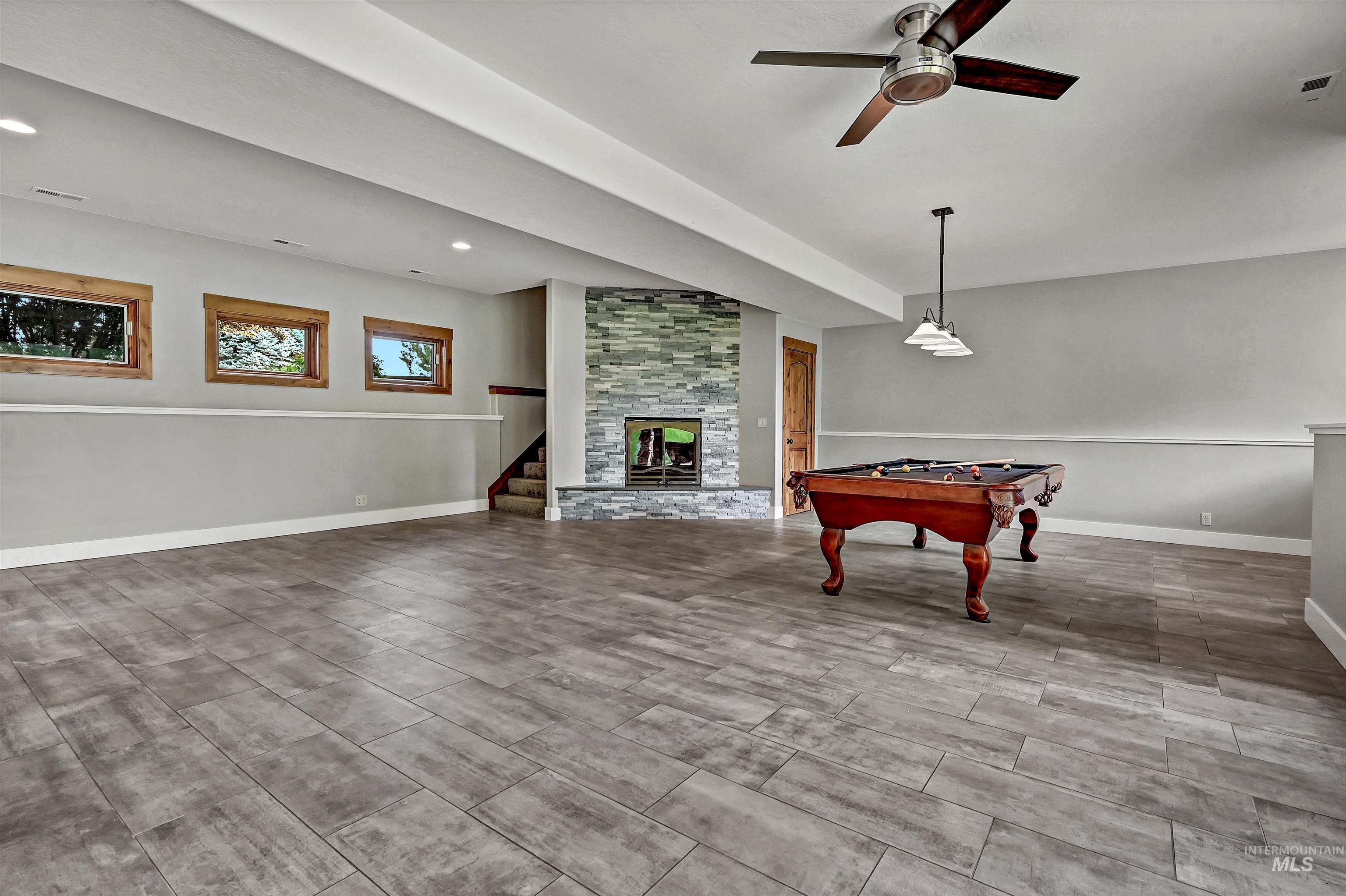 Rec room featuring a fireplace, wood tiled floors, and ceiling fan