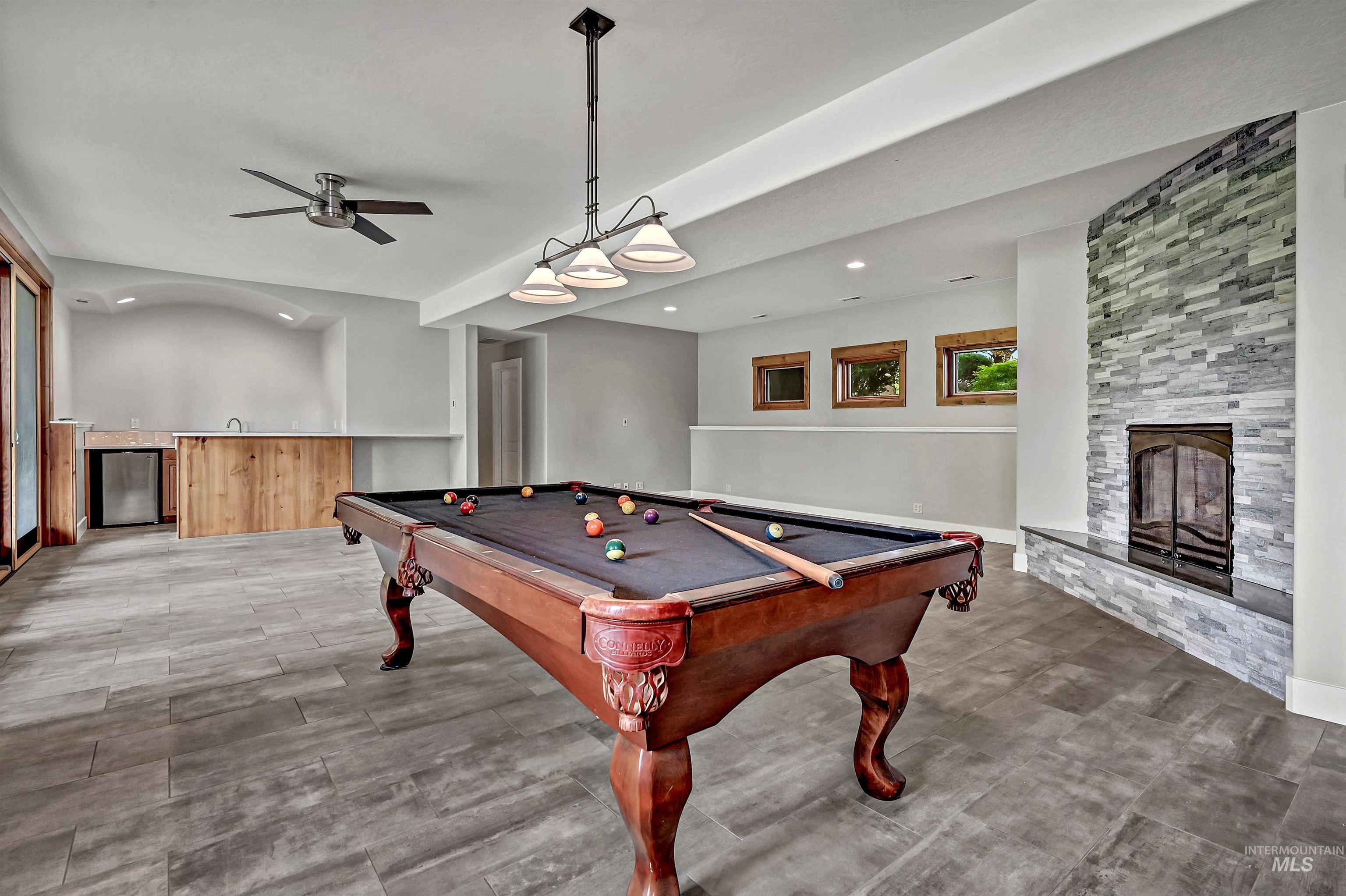 Rec room with pool table, a stone fireplace, ceiling fan, recessed lighting, and wood finished floors