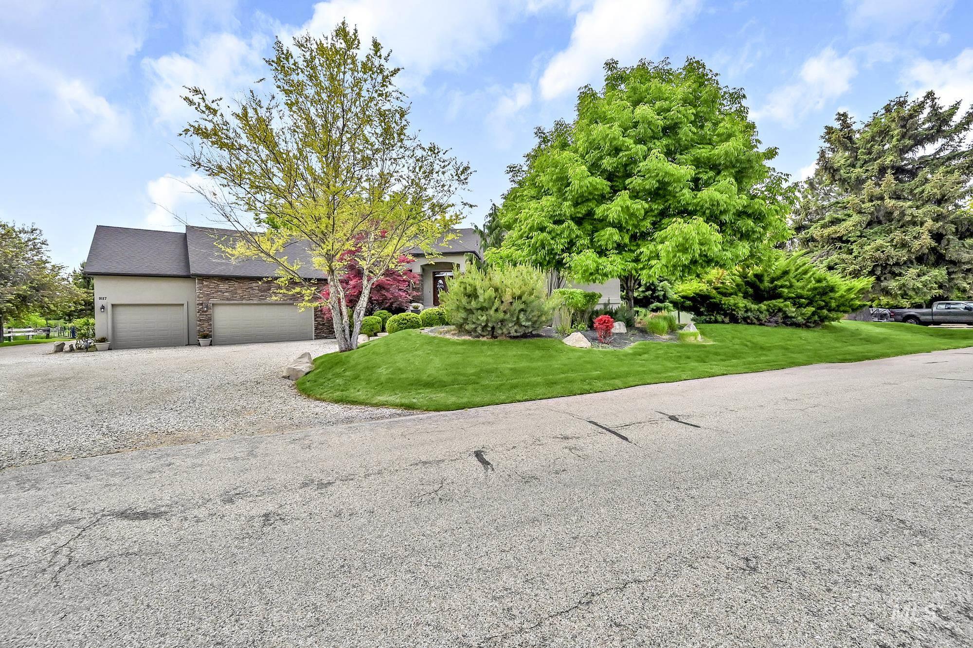 View of front of house featuring a front lawn, gravel driveway, an attached garage, stone siding, and a shingled roof