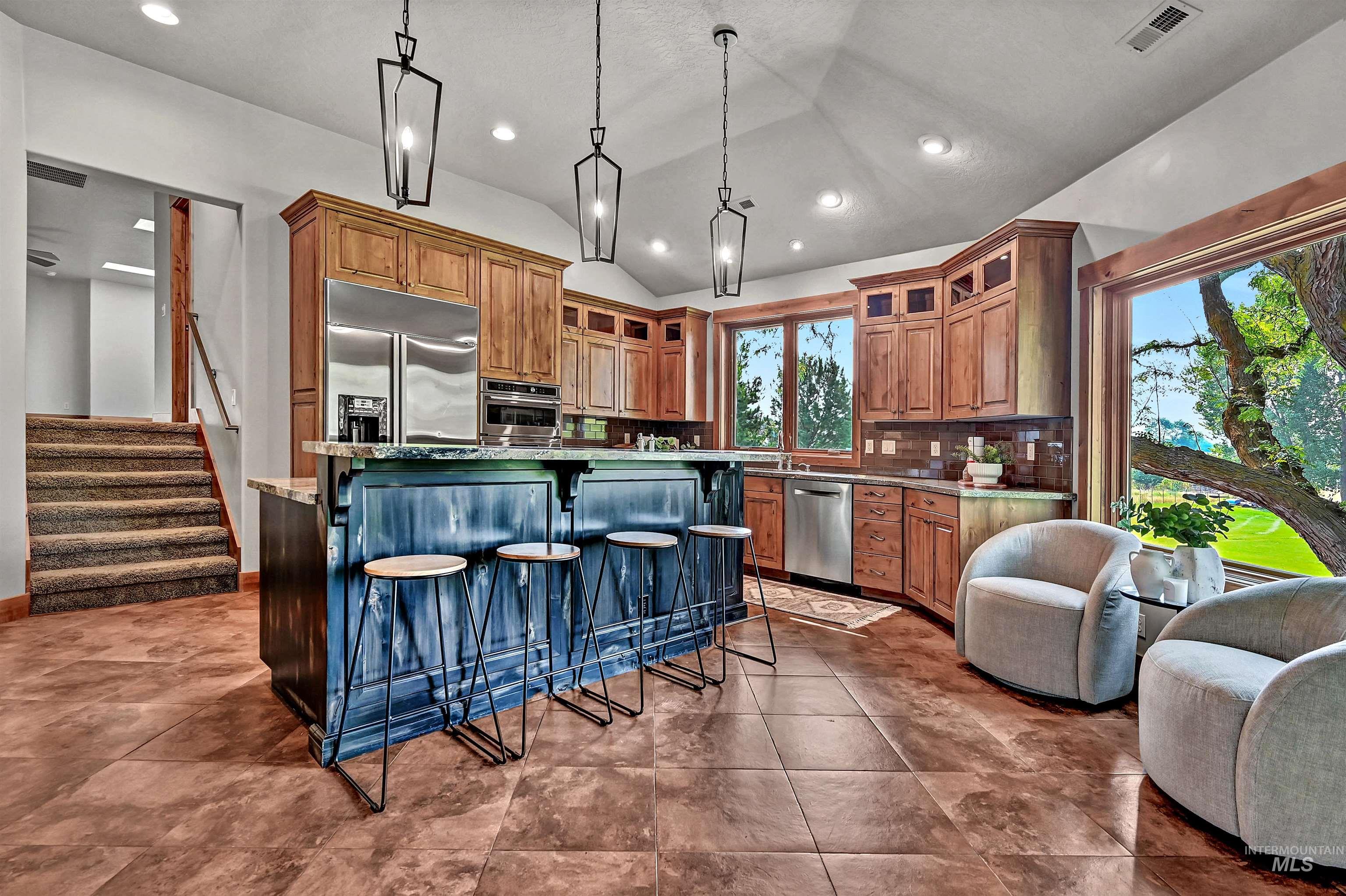 Kitchen with a breakfast bar area, decorative light fixtures, a center island, vaulted ceiling, and brown cabinets