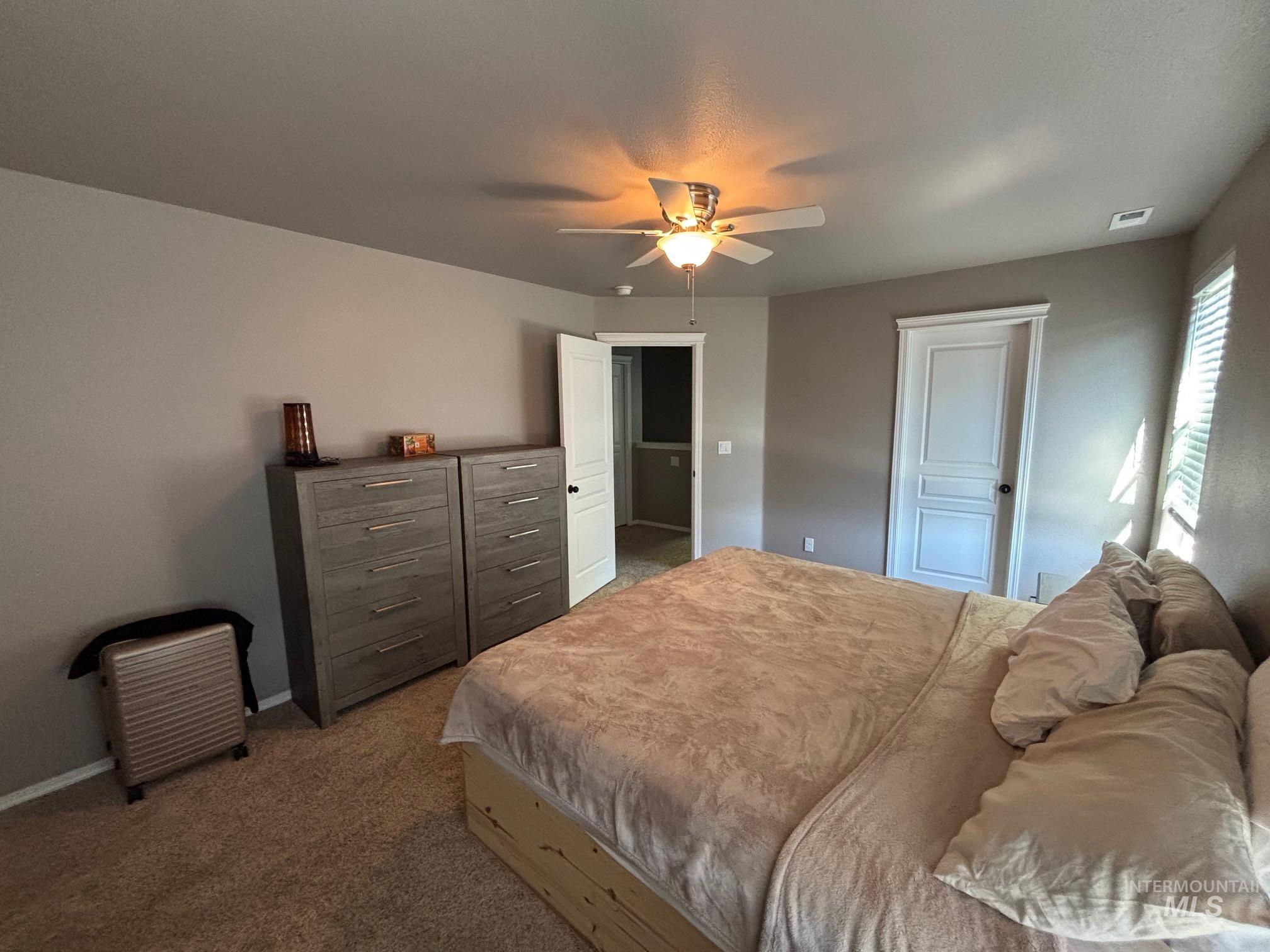 Carpeted bedroom with a ceiling fan and baseboards