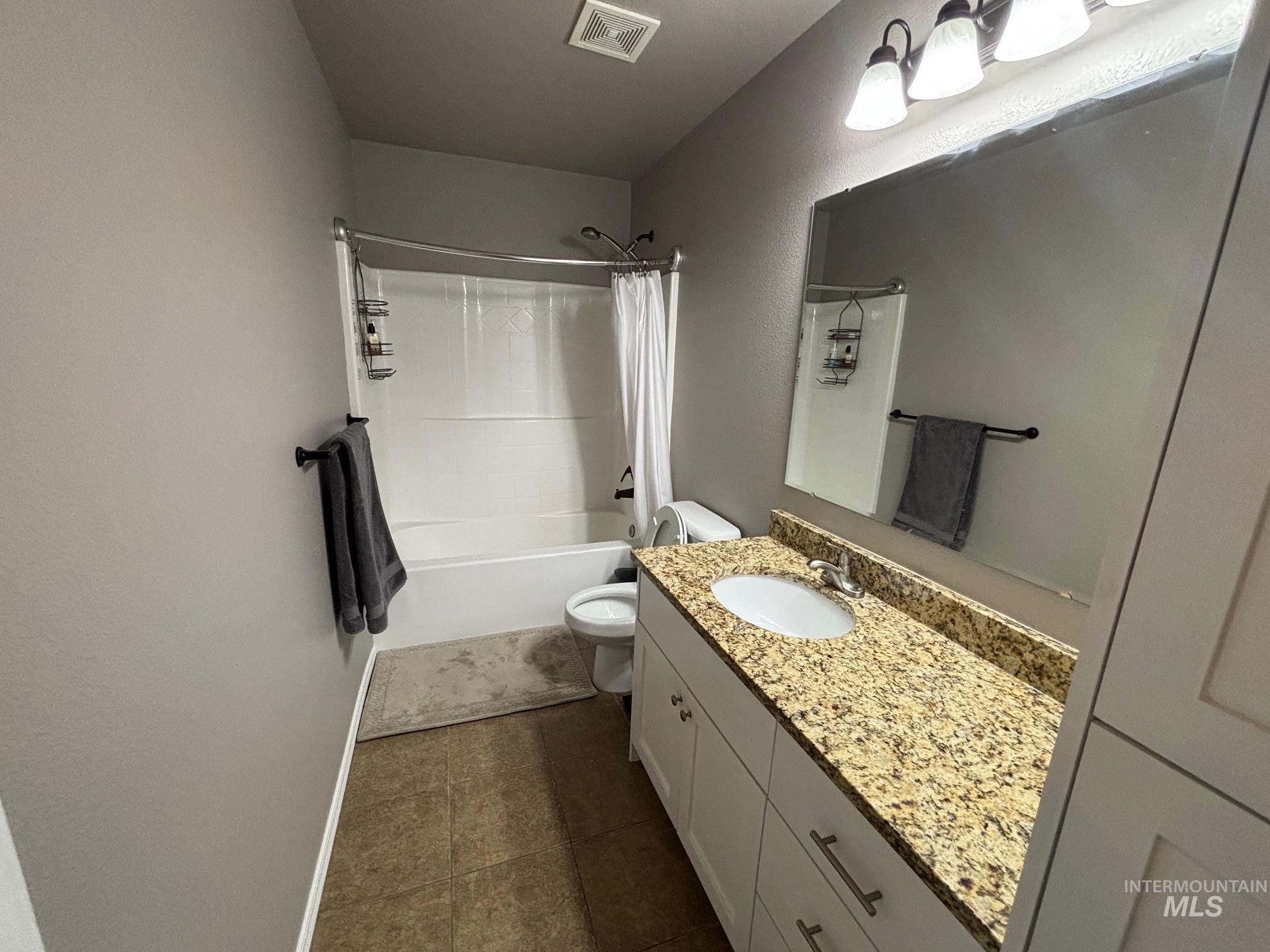 Full bath featuring shower / bathtub combination with curtain, vanity, and dark tile patterned flooring