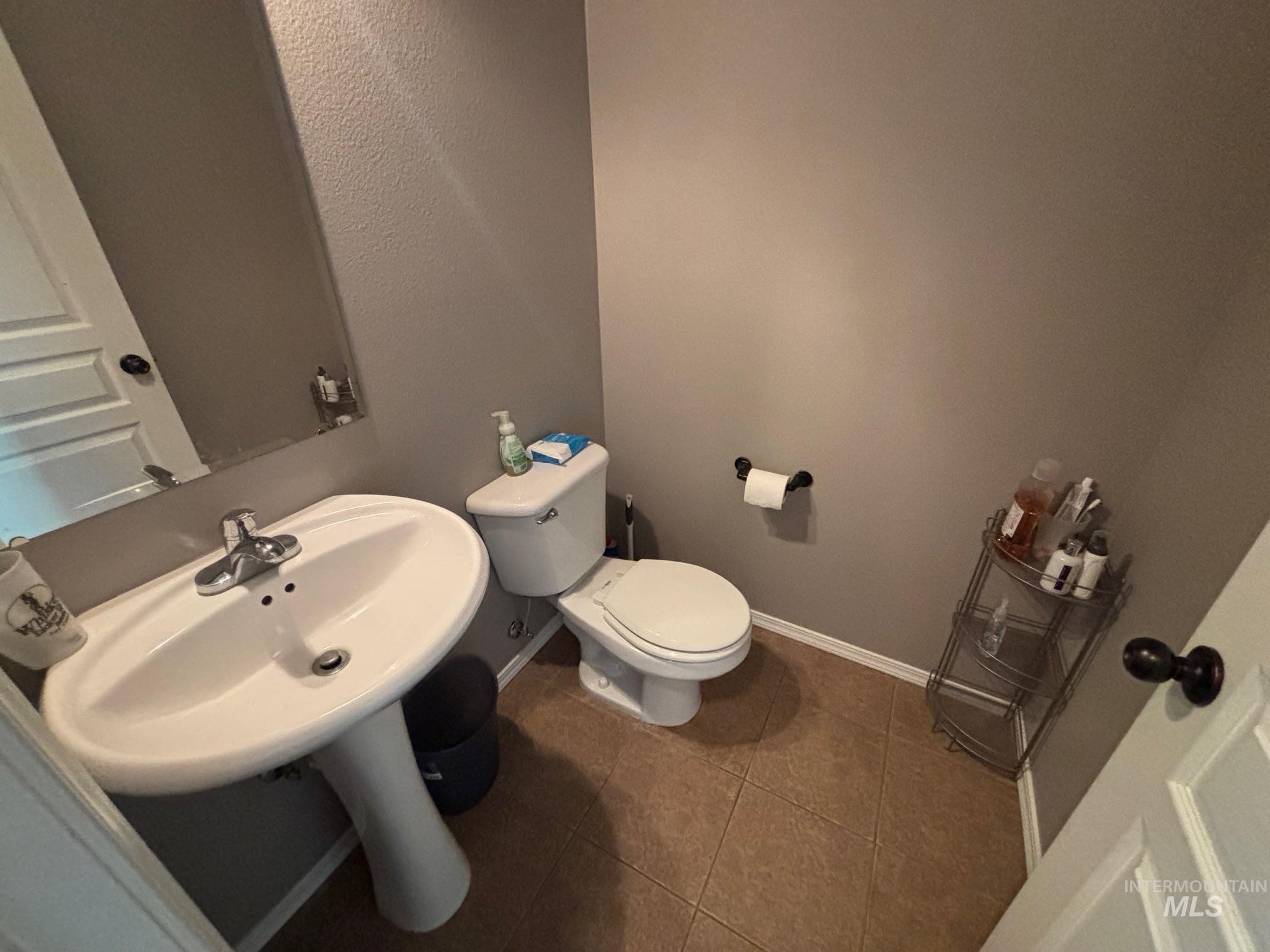 Bathroom featuring dark tile patterned floors and a textured wall