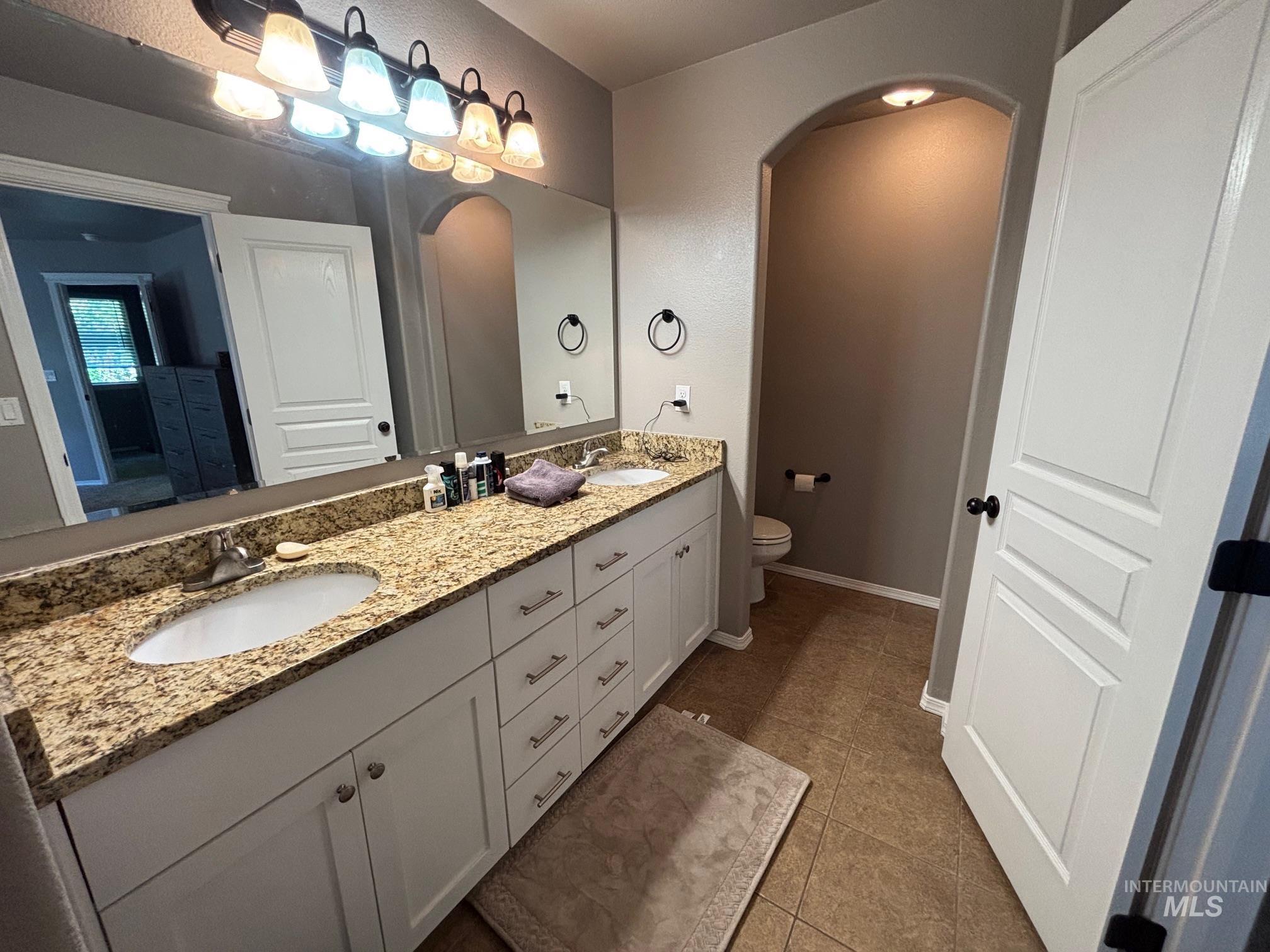 Bathroom featuring double vanity and dark tile patterned floors