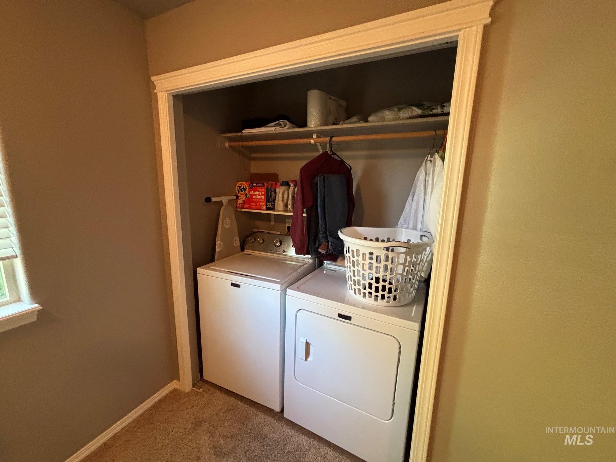 Laundry area featuring light colored carpet and washer and dryer