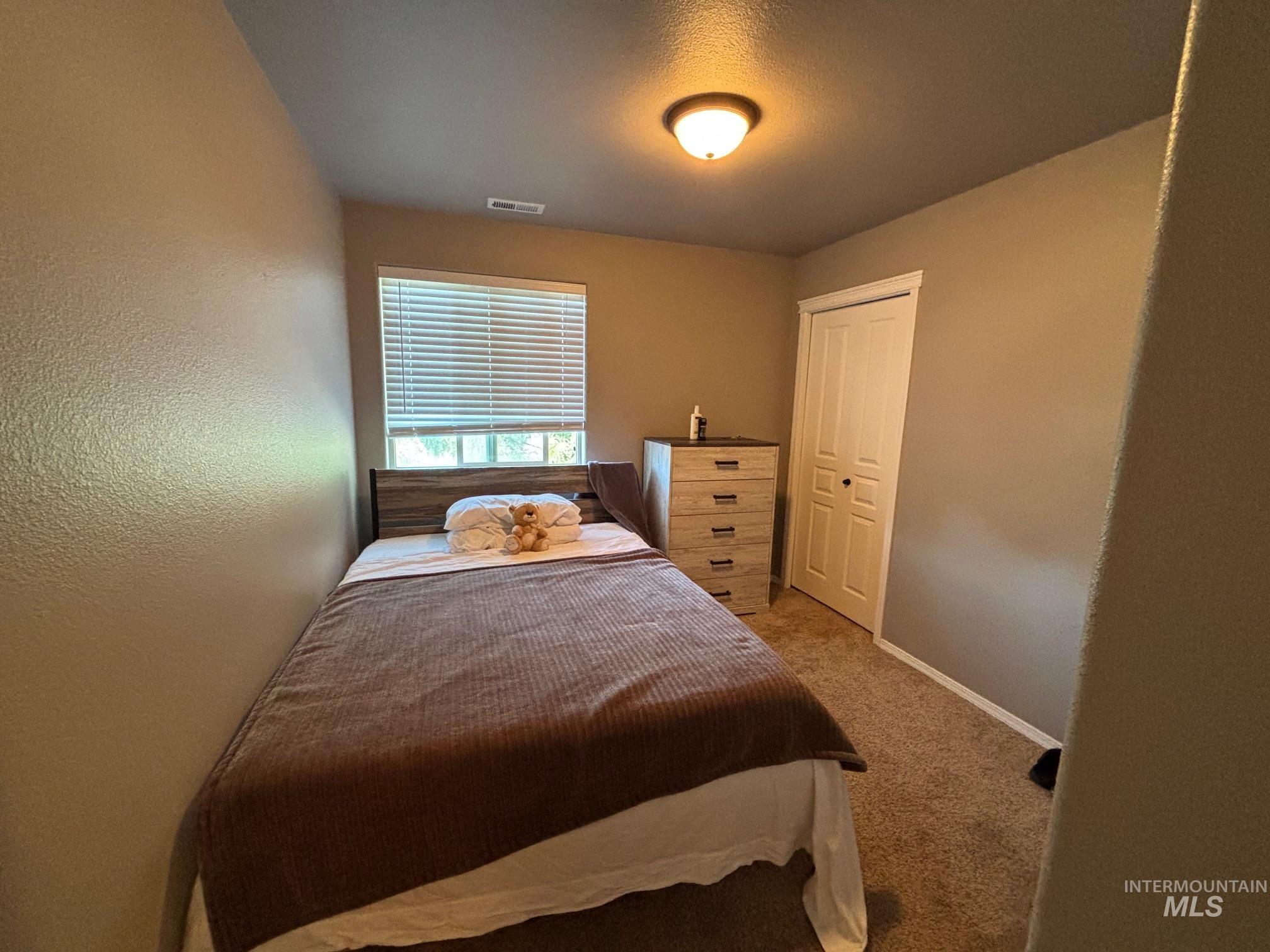 Carpeted bedroom with a closet, a textured wall, and a textured ceiling
