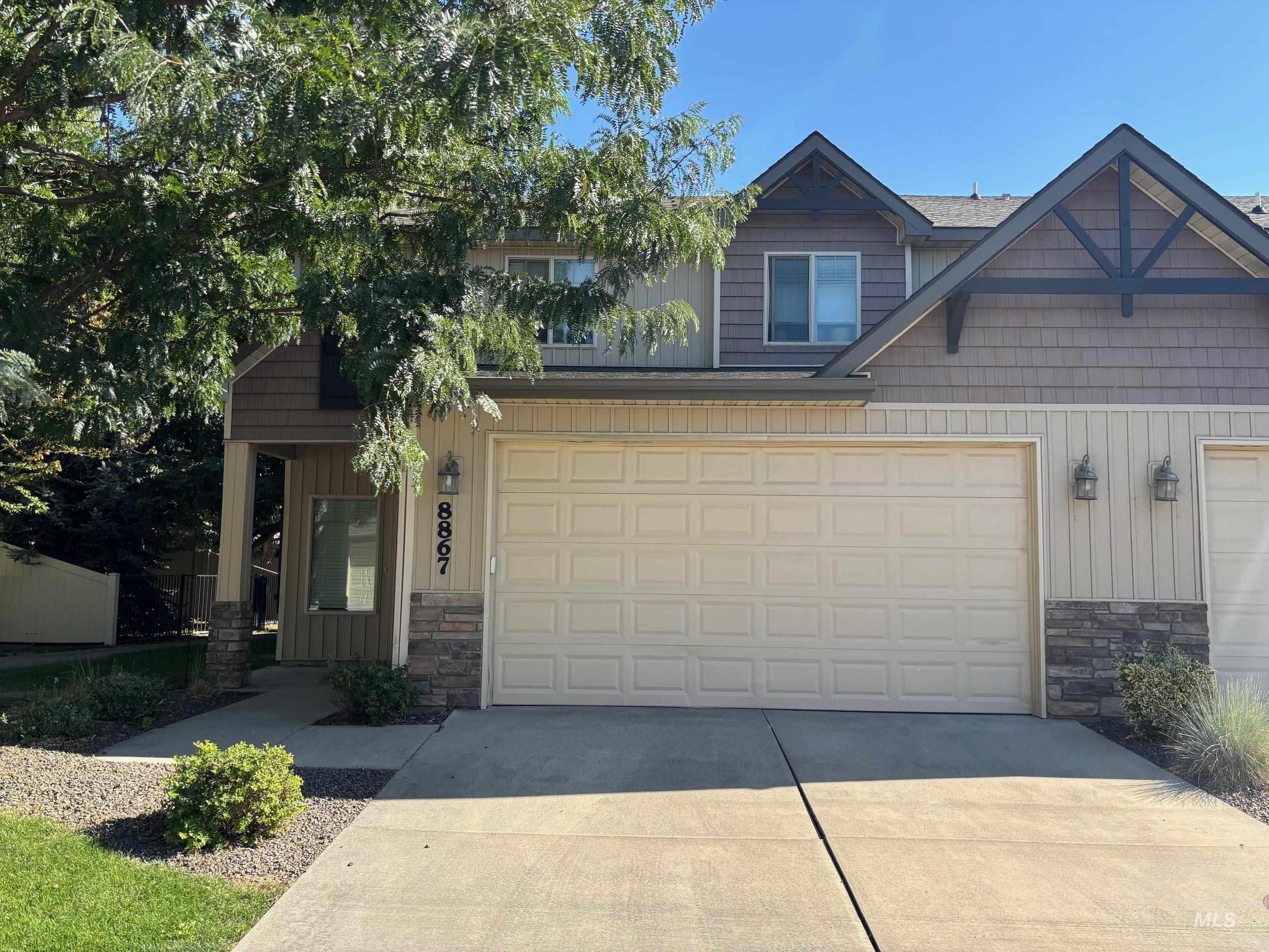 Craftsman-style house featuring stone siding, driveway, board and batten siding, an attached garage, and a porch