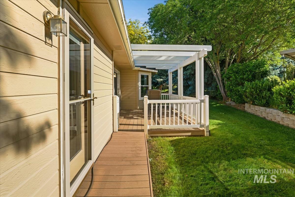 Expansive outdoor decking featuring a white pergola, white baluster railing, and a wood-finish ramp