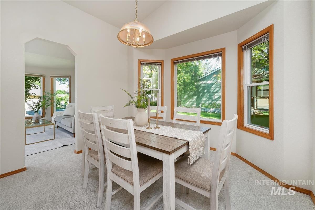 Dining area featuring a bay window, light-toned carpeting, and a chandelier-style light fixture