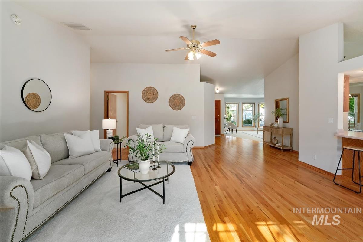 Spacious living area featuring vaulted ceilings with a ceiling fan, recessed lighting, and hardwood flooring