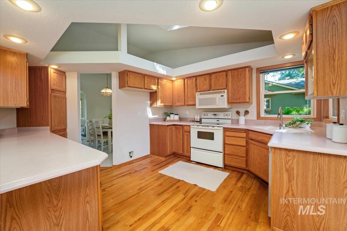 Kitchen featuring wood-finish cabinetry, light-toned countertops, and wood-finish flooring