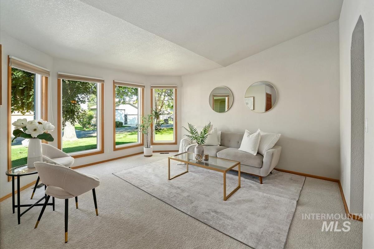 Living area featuring a vaulted ceiling and light-toned carpeting