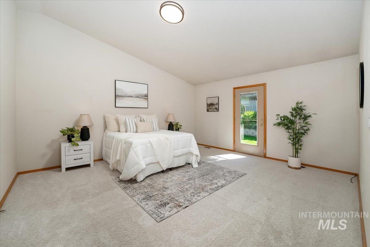 Spacious room featuring vaulted ceilings, light-toned carpeting, and a glass-paneled exterior door