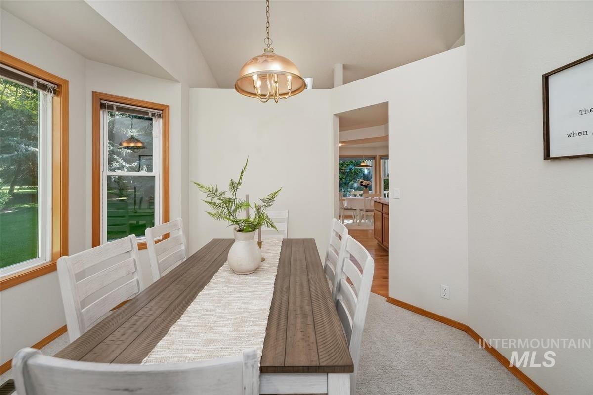 Dining area featuring wood-finish flooring, light grey carpeting, and vaulted ceilings