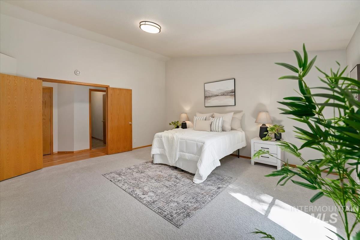 Carpeted room with light neutral wall tones, featuring a flush-mount ceiling light fixture, two wood-finish doors, and matching wood-finish trim
