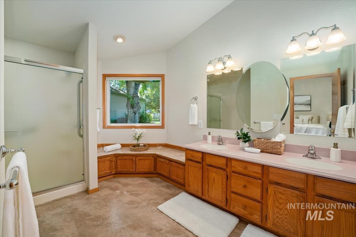 Bathroom featuring a dual vanity with light countertops, wood cabinetry, and an oval mirror