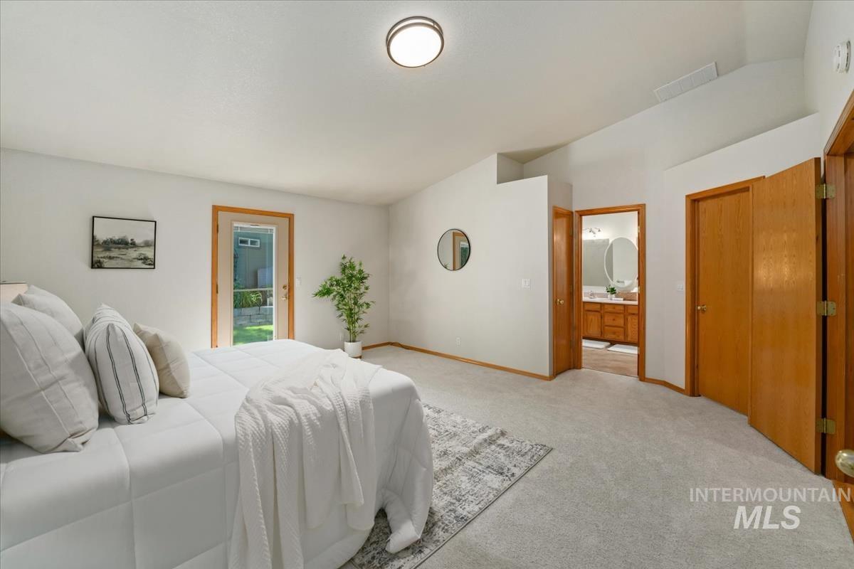 Carpeted bedroom with a vaulted ceiling and direct exterior access