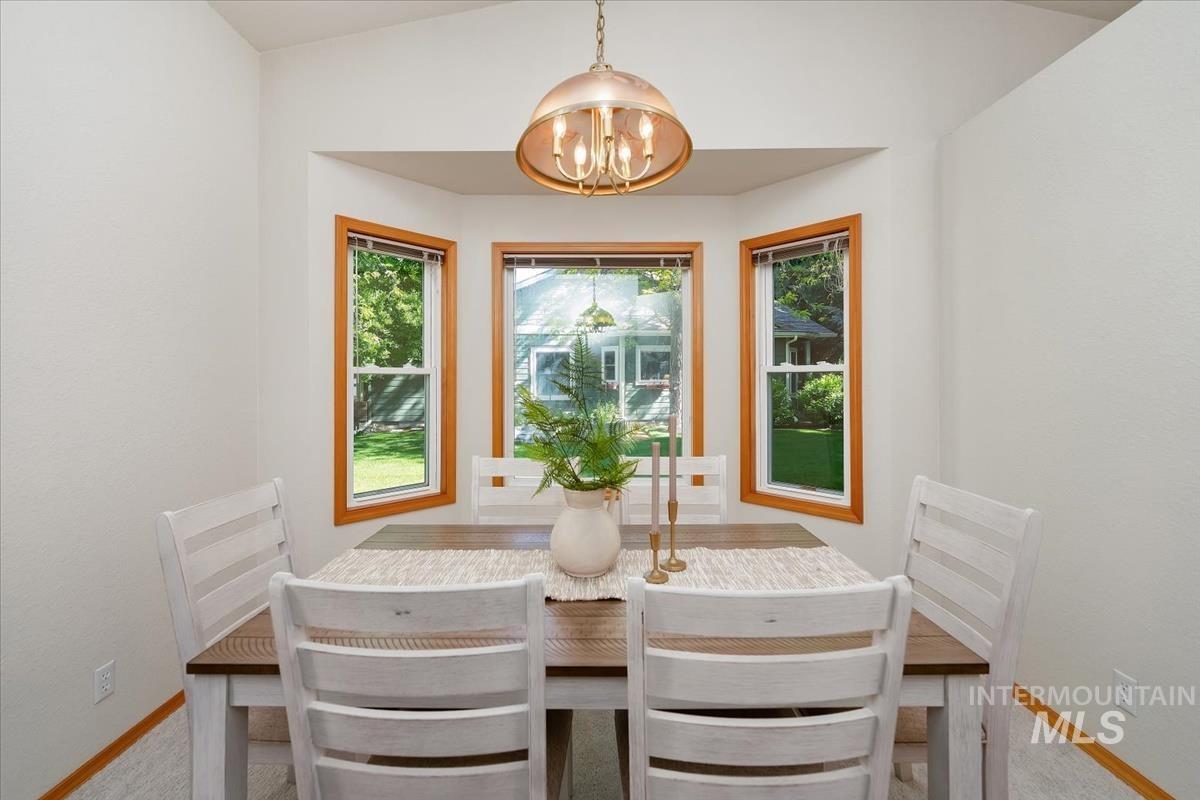 Dining area featuring a vaulted ceiling and a bay window ensemble with warm wood trim