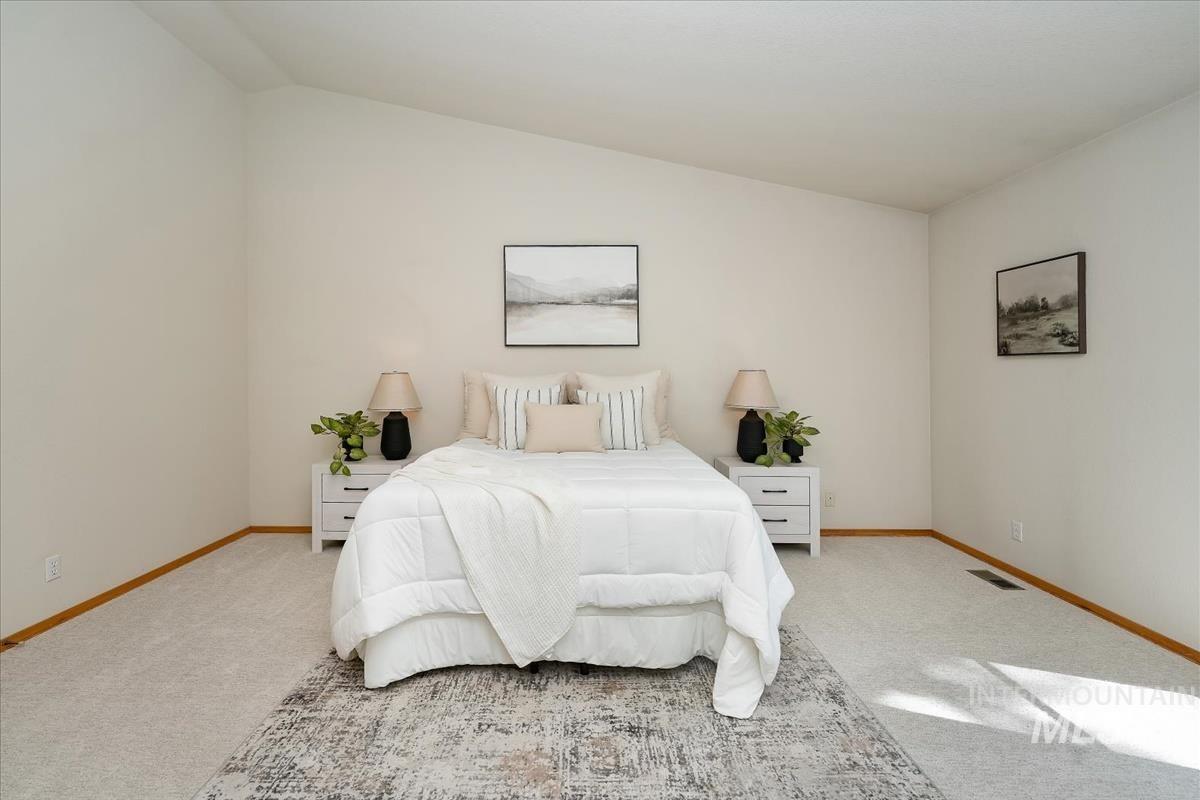 Spacious bedroom featuring vaulted ceilings and neutral wall tones