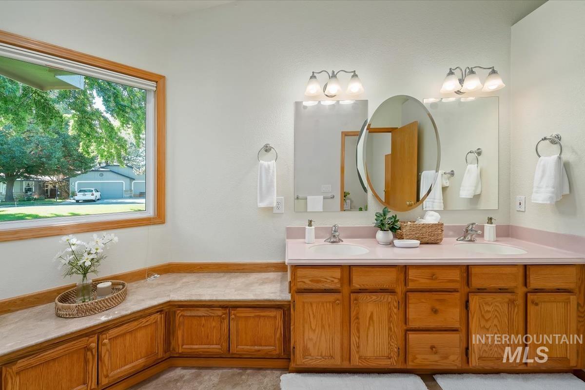 Dual vanity featuring wood-finish cabinetry and light-toned countertops