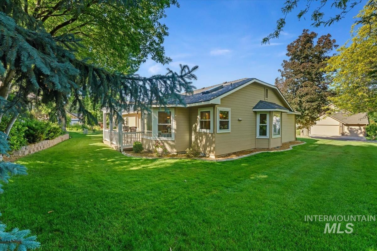 Expansive green lawn surrounds the property, featuring mature trees providing natural shading